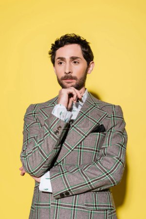 Portrait of stylish model in checkered jacket posing on yellow background 