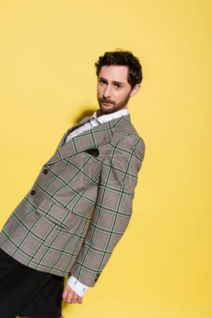 Photo for Stylish man in checkered jacket posing on yellow background with shadow - Royalty Free Image