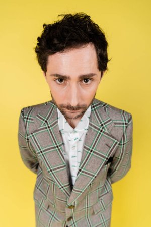 Wide angle view of stylish man looking at camera isolated on yellow  