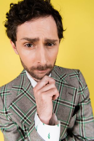 Wide angle view of focused and stylish man looking at camera isolated on yellow  