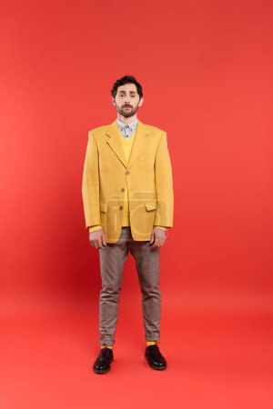 Foto de Longitud completa del modelo de moda en chaqueta amarilla de pie sobre fondo rojo - Imagen libre de derechos