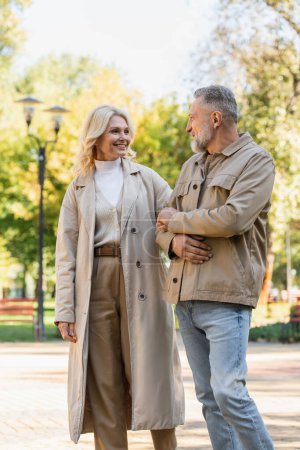 Photo for Smiling mature couple talking while walking in spring park - Royalty Free Image