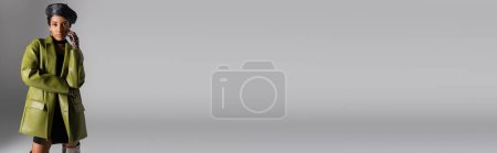 Téléchargez les photos : Modèle afro-américain à la mode en béret et manteau en cuir posé sur gris, bannière - en image libre de droit