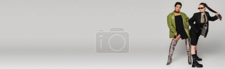 Téléchargez les photos : Femmes élégantes multiethniques en veste et manteau en cuir posant sur fond gris, bannière - en image libre de droit