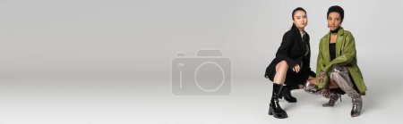 Photo for Asian and african american girlfriends posing in stylish clothes on grey background, banner - Royalty Free Image