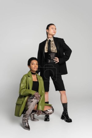 Interracial models in stylish spring clothes posing on grey background
