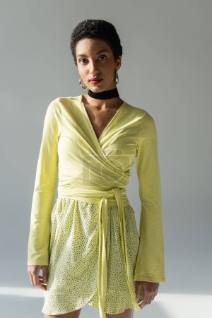 Pretty african american model in spring outfit standing on grey background