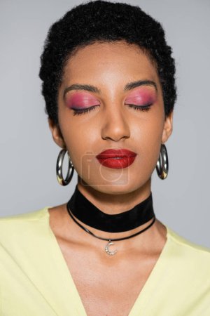 Photo for Portrait of african american woman with colorful makeup closing eyes isolated on grey - Royalty Free Image