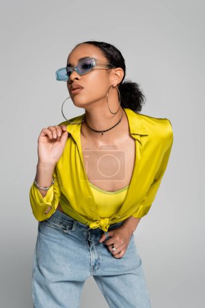 pretty african american woman in blue sunglasses posing isolated on grey 