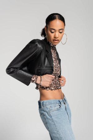 fashionable african american woman in black cropped jacket posing isolated on grey 