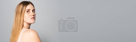 Photo for Woman with freckles on skin looking at camera isolated on grey, banner - Royalty Free Image