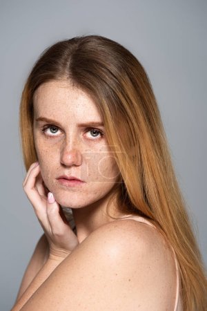 Téléchargez les photos : Portrait de modèle taches de rousseur avec problème de peau en regardant la caméra isolée sur gris - en image libre de droit