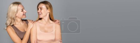 Foto de Modelo despreocupado con amigo abrazador de acné aislado en gris, pancarta - Imagen libre de derechos