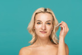 blonde woman with acne on face holding pipette with moisturizing serum isolated on turquoise t-shirt #648034382