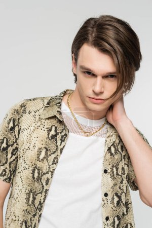 trendy pansexual person in animal print blouse posing with hand near neck isolated on grey