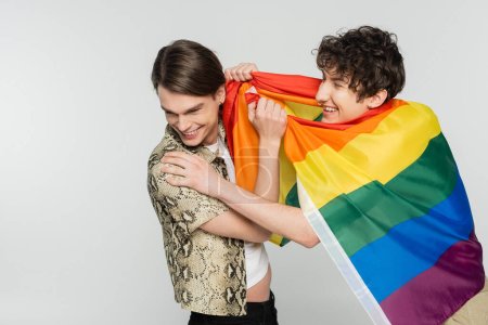 Foto de Alegres socios más grandes con la bandera del arco iris divertirse aislado en gris - Imagen libre de derechos