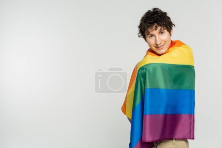 Photo for Happy pansexual model covered with rainbow flag smiling at camera isolated on grey - Royalty Free Image