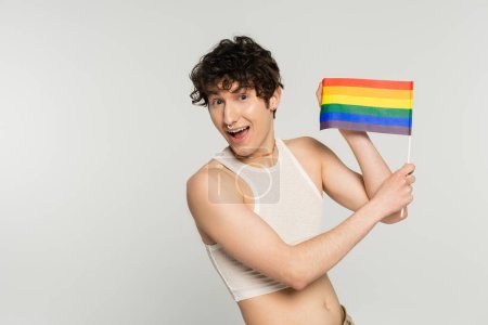 Photo for Amazed pangender person showing small lgbt flag at camera isolated on grey - Royalty Free Image