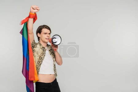 trendy bigender person with lgbt flag shouting in loudspeaker isolated on grey