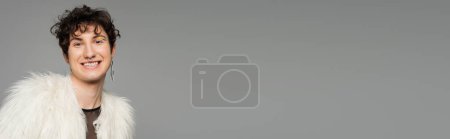 Téléchargez les photos : Gai bigender personne en fausse fourrure blanche veste et boucle d'oreille en argent isolé sur gris, bannière - en image libre de droit