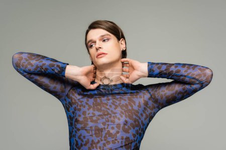 Photo for Fashionable pansexual person in blue animal print top touching neck and looking away isolated on grey - Royalty Free Image