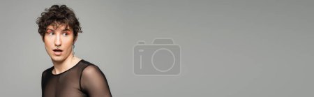 Foto de Asombrado persona pansexual con la boca abierta mirando hacia otro lado aislado en gris, pancarta - Imagen libre de derechos
