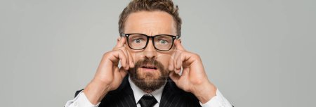 Téléchargez les photos : Homme d'affaires stressé en tenue formelle et lunettes regardant la caméra isolée sur gris, bannière - en image libre de droit