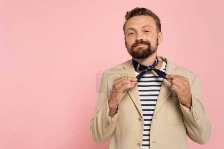 Photo for Pleased french man in stylish clothes adjusting neck scarf isolated on pink - Royalty Free Image
