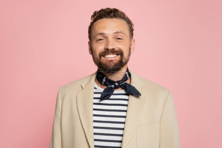 overjoyed french man in blazer and neck scarf looking at camera isolated on pink 