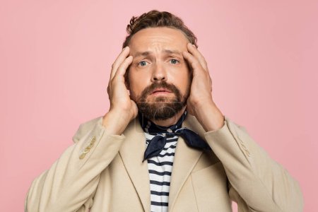 Photo for Stressed man in blazer and neck scarf looking at camera while holding head isolated on pink - Royalty Free Image