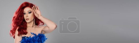 Téléchargez les photos : Drag queen en perruque rouge et robe regardant caméra isolée sur gris, bannière - en image libre de droit