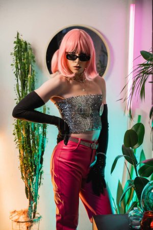 Foto de Moda drag queen en peluca rosa y top brillante posando en casa - Imagen libre de derechos