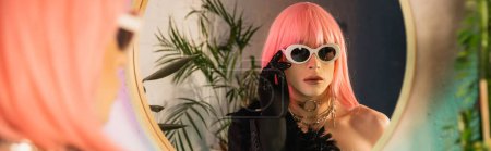 Foto de Moda drag queen en peluca rosa con gafas de sol cerca del espejo en casa, pancarta - Imagen libre de derechos