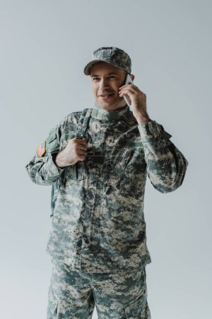 Foto de Soldado feliz en uniforme del ejército hablando en el teléfono inteligente aislado en gris - Imagen libre de derechos