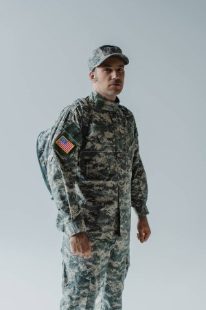 American soldier in army uniform with national flag standing isolated on grey 