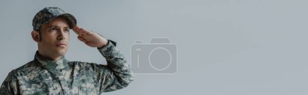 Photo for Soldier in military uniform crying while saluting during memorial day isolated on grey, banner - Royalty Free Image