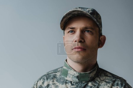 triste militar en uniforme llorando durante el día conmemorativo aislado en gris 