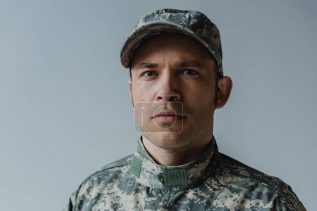 soldado molesto en uniforme militar llorando durante el día conmemorativo aislado en gris 