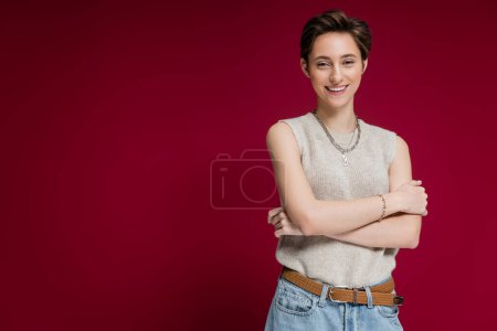 Photo for Happy young woman with short hair smiling and looking at camera on dark red background - Royalty Free Image
