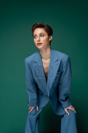 Photo for Young well dressed model with short hair posing in blue suit on turquoise background - Royalty Free Image