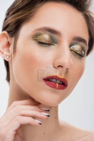 Photo for Young woman with short hair and bright makeup posing with closed eyes isolated on grey - Royalty Free Image