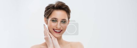 Photo for Joyful young woman with shimmery eye makeup smiling isolated on grey, banner - Royalty Free Image