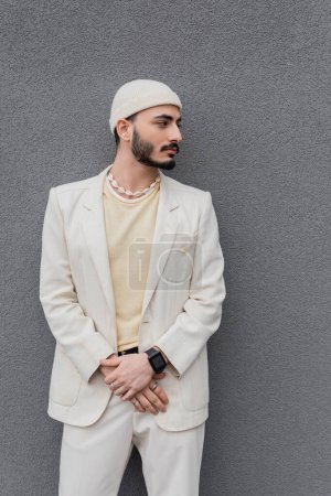 Photo for Well dressed gay man in beige suit and hat standing near wall outdoors - Royalty Free Image