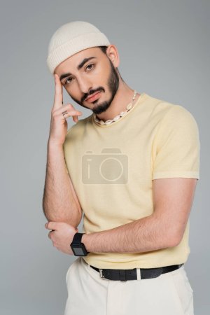 Porträt eines modischen Homosexuellen mit Hut posiert isoliert auf grau  