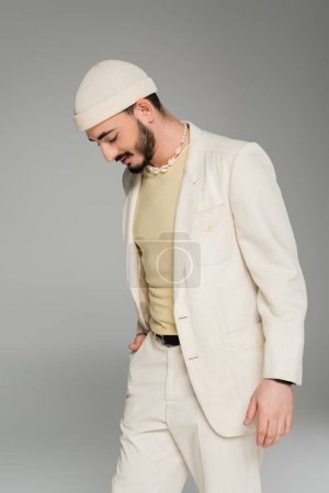 Photo for Trendy homosexual man in suit and hat posing isolated on grey - Royalty Free Image