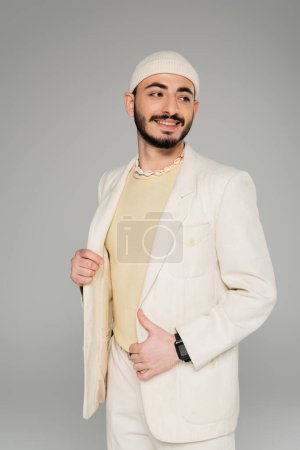 Téléchargez les photos : Insouciant gay l'homme dans beige veste et chapeau regarder loin isolé sur gris - en image libre de droit