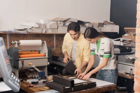 good looking publisher explaining work to colleague in print center 