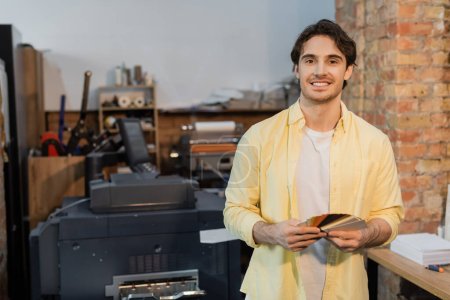 happy man choosing color while holding samples in modern print center