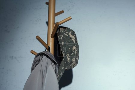 Gorra militar colgando en la percha del piso en casa por la noche 