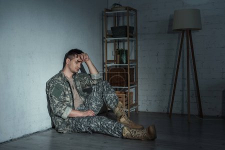Frustrado militar con ptsd sentado en el suelo después del regreso a casa 